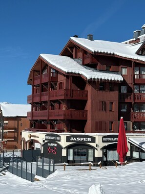 A multi-story wooden building with balconies and a snow-covered roof, featuring a restaurant named 'JASPER' at the ground level. - Premium Ski-in/Ski-out Apartment with Panoramic View | Montana 1st Floor (Les Belleville)