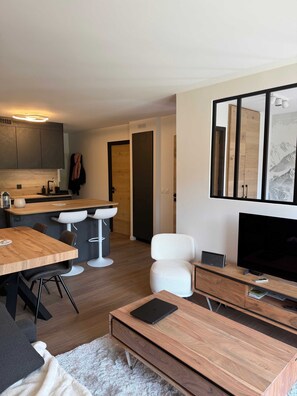 A modern living room with a wooden coffee table, a TV, and a comfortable seating area. - Premium Ski-in/Ski-out Apartment with Panoramic View | Montana 1st Floor (Les Belleville)