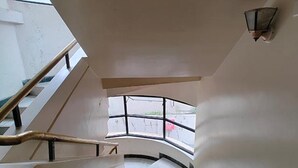 A staircase with a handrail and a view of the outside through a window. - Fabhotel Ramesh Inn (Rajgurunagar)