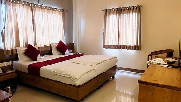A hotel room with a bed, a desk, and curtains. - Fabhotel Ramesh Inn (Rajgurunagar)