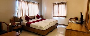A hotel room with a bed, a desk, and curtains. - Fabhotel Ramesh Inn (Rajgurunagar)