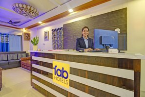 Un mostrador de recepción de hotel con diseño moderno, una recepcionista y un cartel que indica que es un establecimiento de Fabol Hotels.