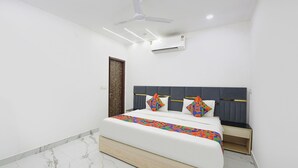 Une chambre à coucher moderne, dotée d’un lit, d’un ventilateur de plafond, d’un climatiseur et d’un sol carrelé en marbre.