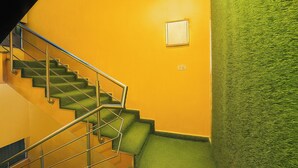 Un escalier avec des rampes en métal menant à un palier agrémenté d’un mur végétal et d’un tableau encadré.