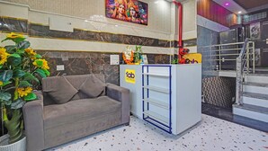 Ein Hotel-Empfangsbereich mit einer Couch, einem Empfangstresen und einem farbenfrohen Wandgemälde.