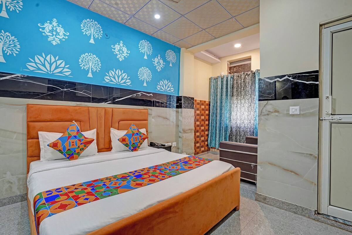 Een moderne hotelkamer met een groot bed, een blauwe wand met boommotieven, een marmeren accentwand en uitzicht op buiten.