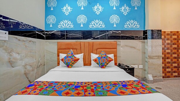 Ein Hotelzimmer mit einem Bett, einer blauen Wand mit Baummustern, einem Holz-Kopfschild und einer gemusterten Bettdecke.
