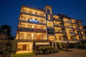 Un hotel a più piani con balconi, un cartello con la scritta 'FabHotels' e un cartello con la scritta 'New Moon Home Stay'.