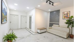 A modern interior with a white sofa, a bench, and a potted plant. - Fabhotel The New Moon (New Delhi)