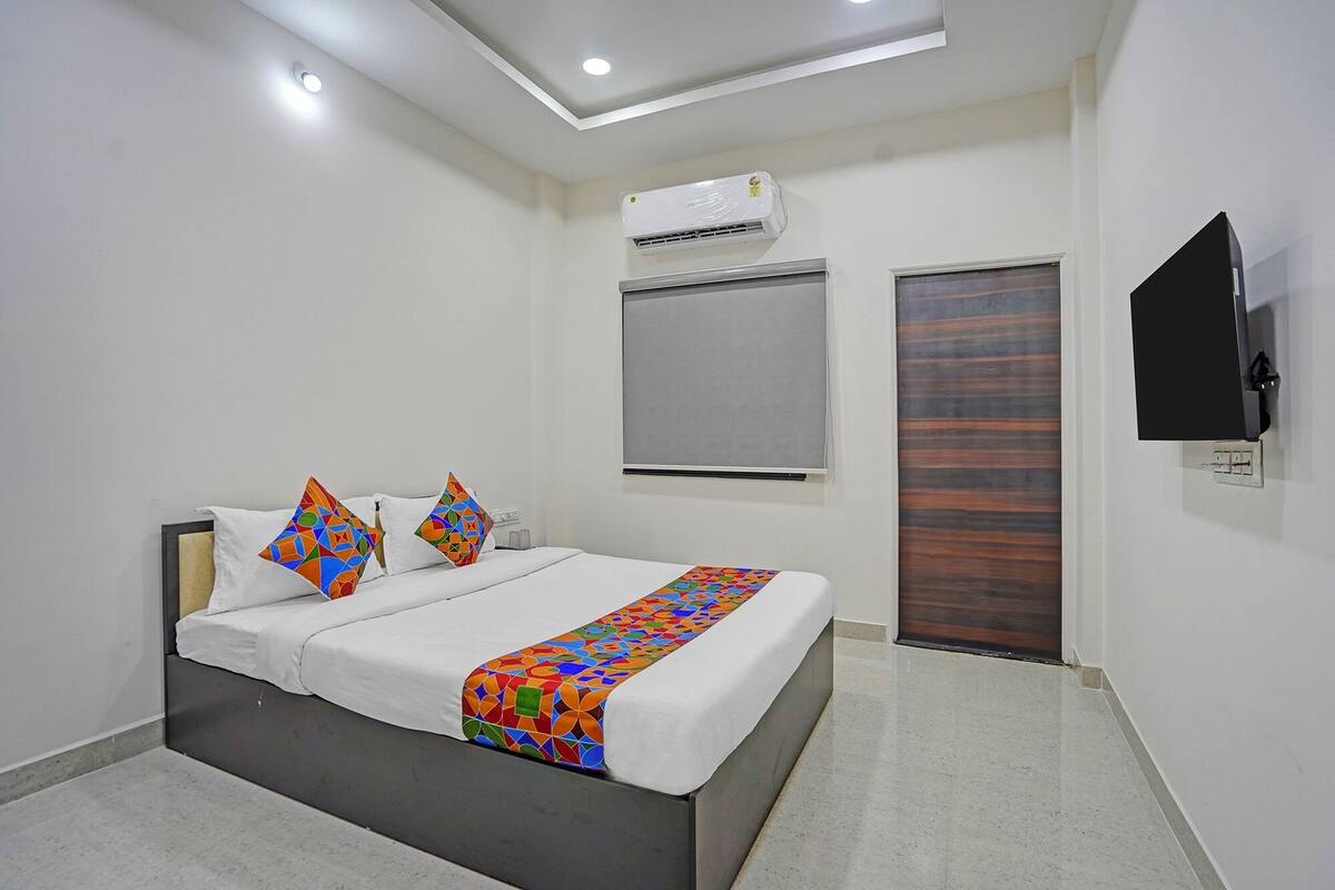 A modern bedroom with a bed, air conditioning unit, and a television on the wall.