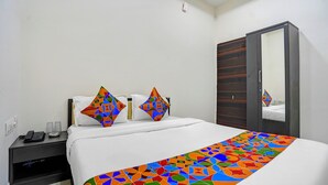 A hotel room with a bed, two pillows, a bedside table with a phone, and a wardrobe.