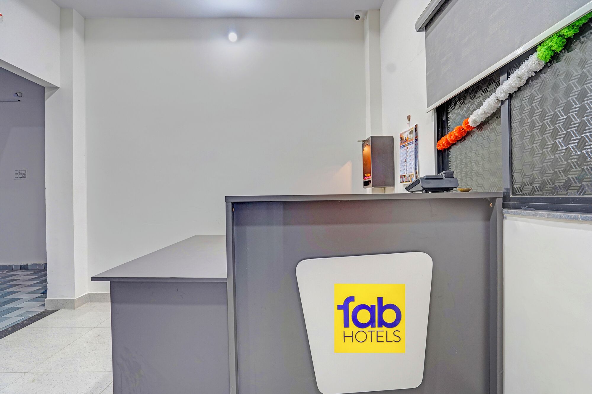 A reception desk with a 'fab hotels' sign, a small plant, and a calendar on the wall.