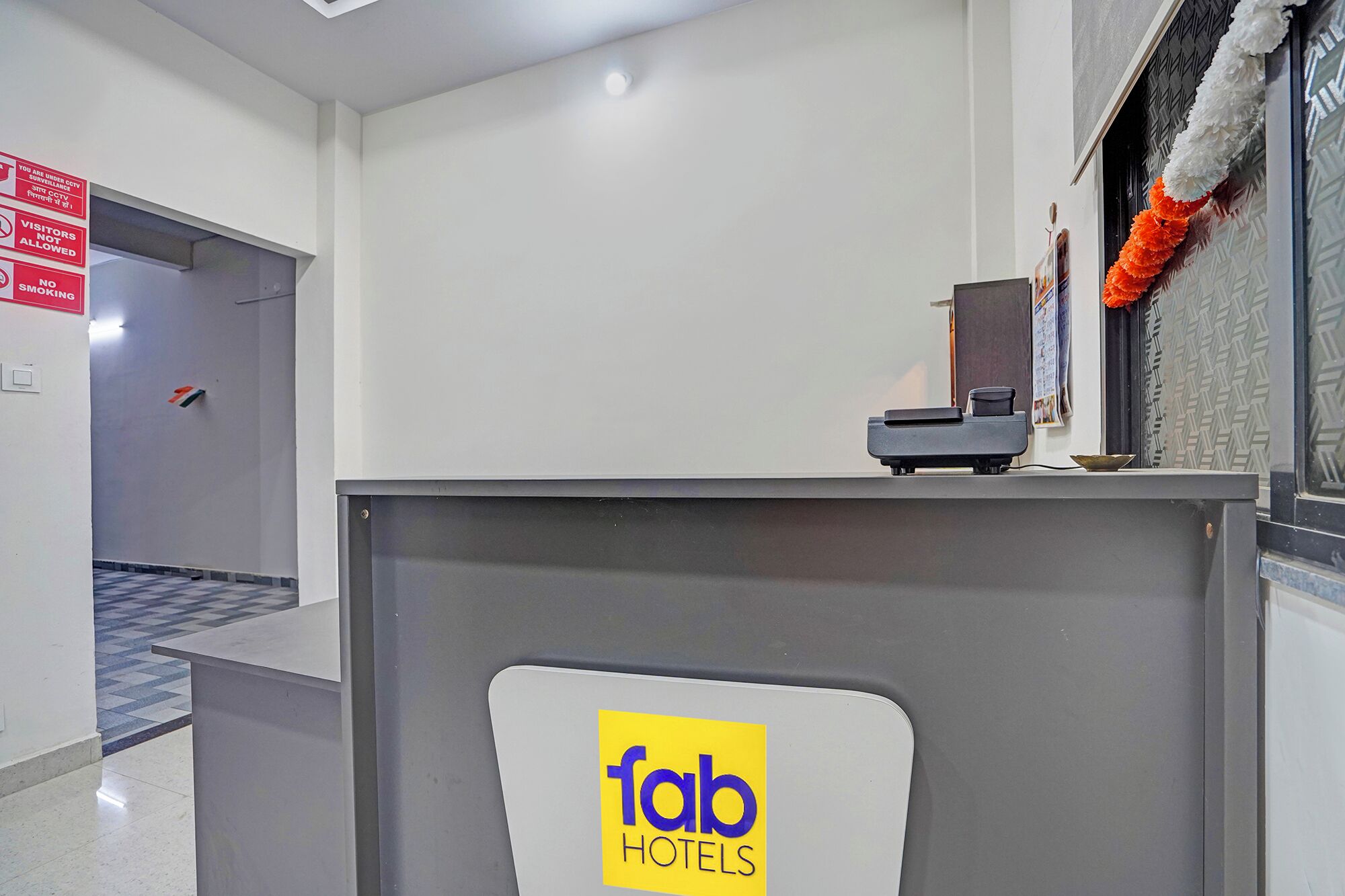 Un mostrador de recepción de hotel con un letrero que indica vigilancia por cámaras de seguridad y prohibido fumar.