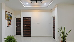 A hallway with two wooden doors, a ceiling light, and a potted plant.