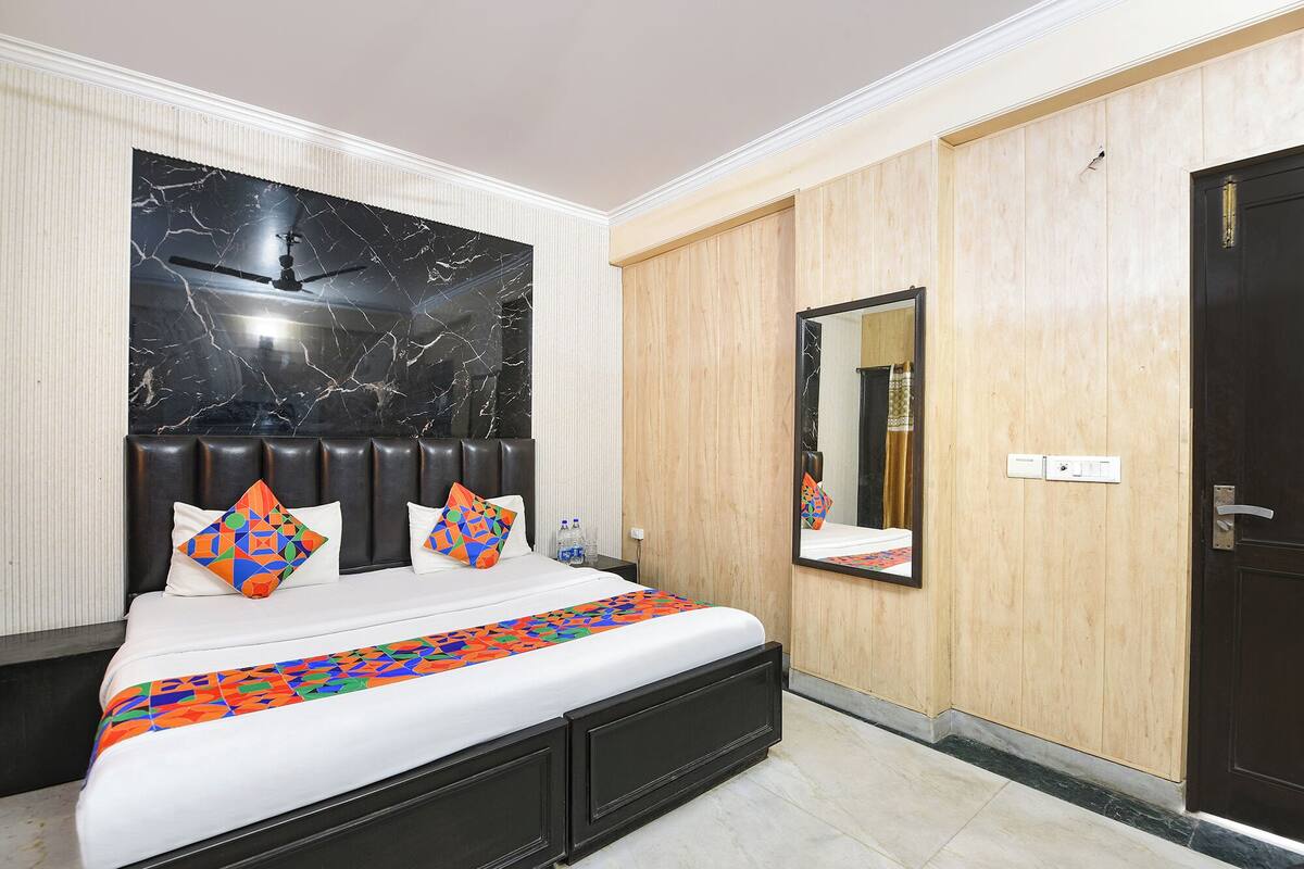 A bedroom with a bed, a headboard, a mirror, and a door.