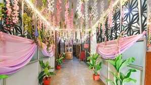 Un couloir décoré de guirlandes de fleurs et agrémenté de plantes en pot.