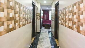 A hallway with a patterned wall, a marble floor, and a purple sofa in the distance. - Via The Heights (New Delhi)