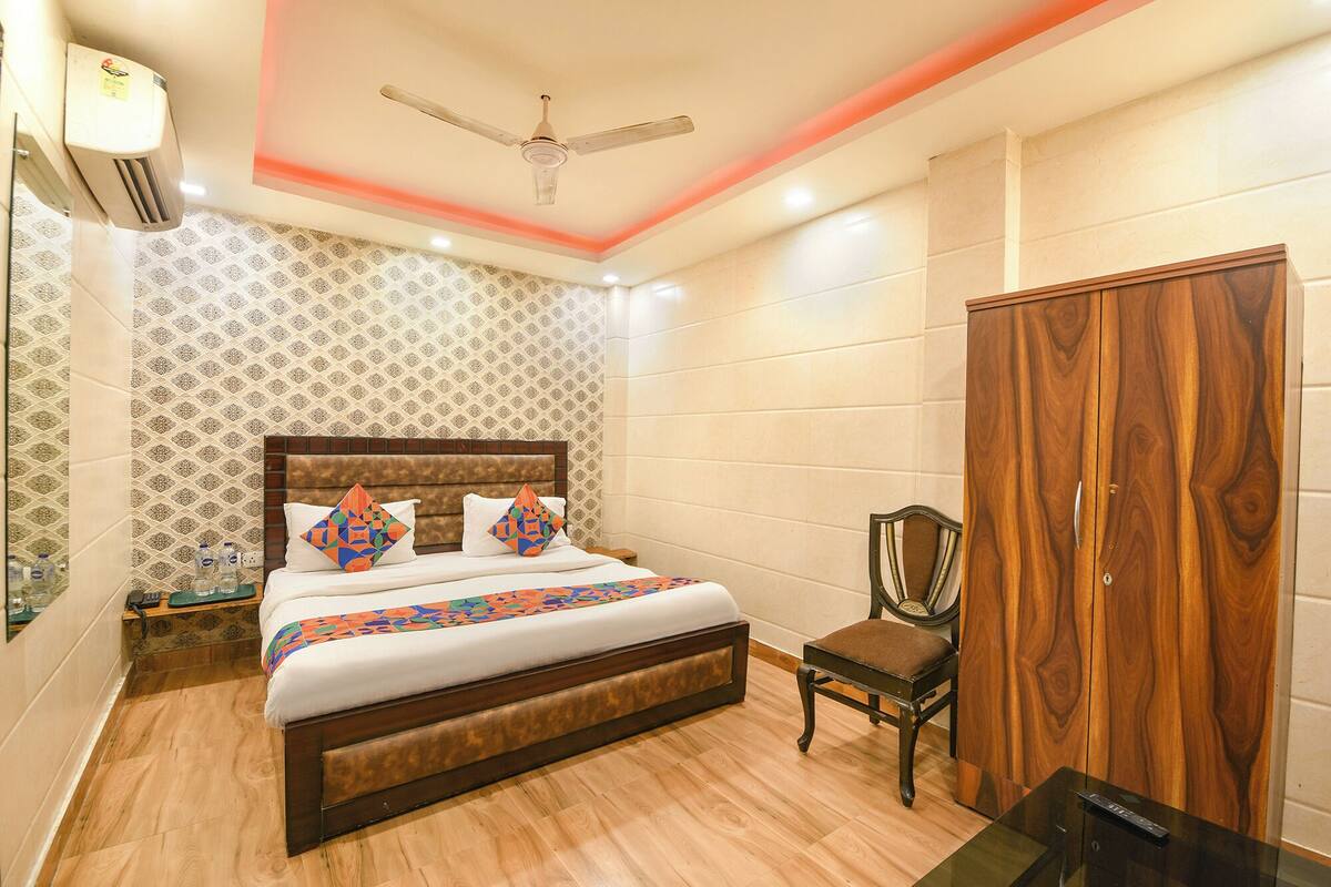 A bedroom with a wooden bed, a ceiling fan, a wardrobe, and a chair.
