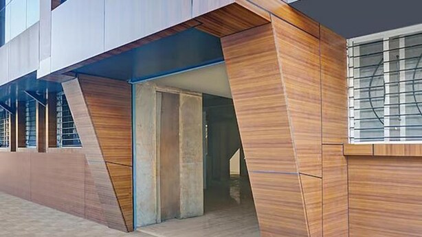 A modern building with a unique architectural design, featuring a combination of wooden panels and glass windows. - Fabhotel Stay One (Mawal)