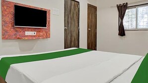 A room with a bed, a television mounted on the wall, and two doors. - Fabhotel Stay One (Mawal)