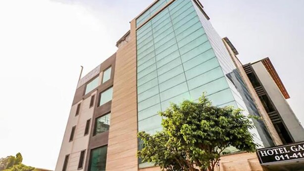 Edifici d'hotel modern amb façana de vidre i un rètol que indica el nom i el número de contacte.