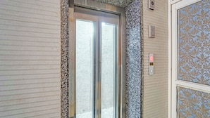 An elevator with a metallic door and a digital display showing the number 0. - Fabhotel Moonlit (Noida)