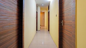 Passadís estret amb portes de fusta i parets grogues, que condueix a una habitació amb terra de rajola.