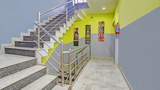 Un escalier avec des rampes en métal, des marches en granit et un extincteur fixé au mur.