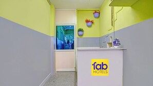Una zona de recepció amb un senyal de 'fab hotels', una finestra amb vista i plantes en maceta a la paret.