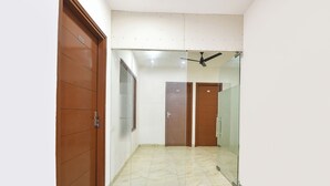 Un pasillo con puerta de vidrio, puerta de madera y ventilador de techo.