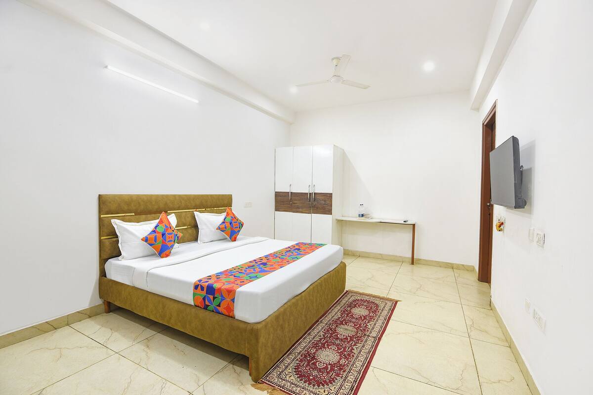 A bedroom with a bed, a wardrobe, a desk, and a television.