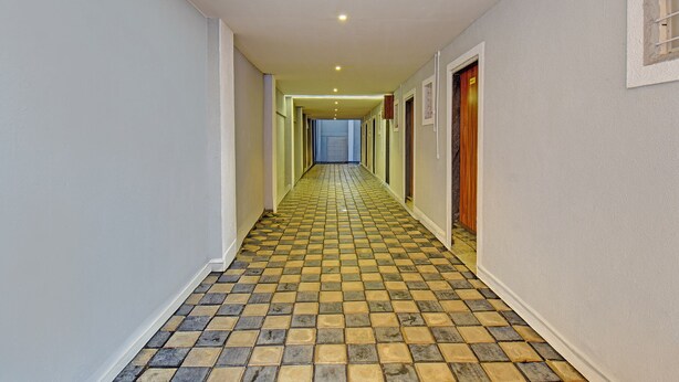 A hallway with patterned flooring and doors on both sides leading to rooms. - Fabhotel Stay Inn Lodge (Pune)