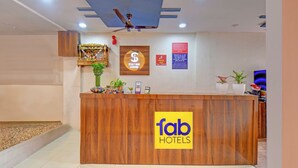 A hotel reception desk with a wooden finish, a ceiling fan, and a sign for 'fab hotels'. - Fabhotel Stay Inn Lodge (Pune)