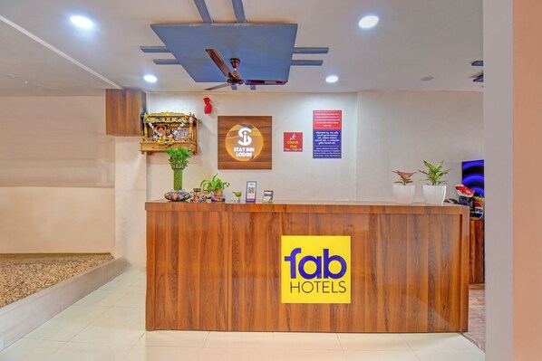 A hotel reception desk with a wooden finish, a ceiling fan, and a sign for 'fab hotels'. - Fabhotel Stay Inn Lodge (Pune)
