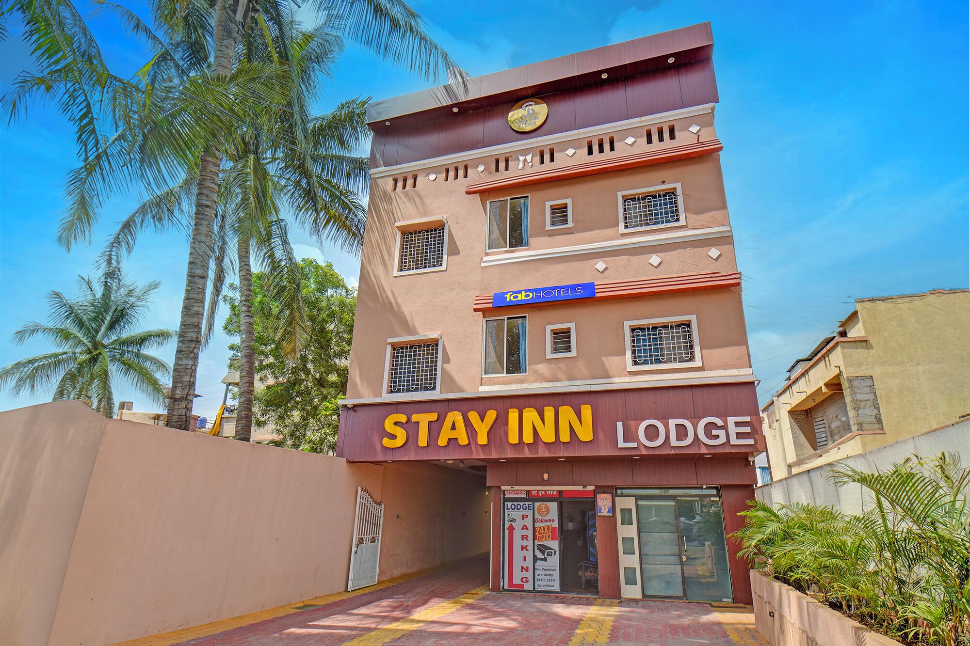 Um edifício com vários andares, com a placa 'Stay Inn Lodge' e a placa 'Fab Hotels' em cima.
