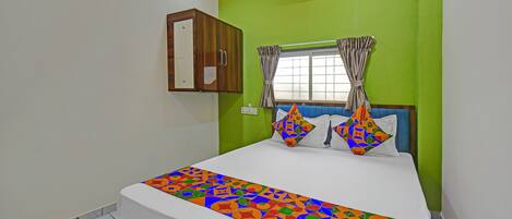 Un dormitorio con cama, ventana con cortinas, aire acondicionado de pared y un armario de madera.