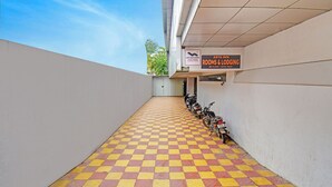 Un sol  à carreaux mène à un bâtiment où, au troisième étage, on peut voir une enseigne indiquant « Arya Inn Rooms & Lodging ».
