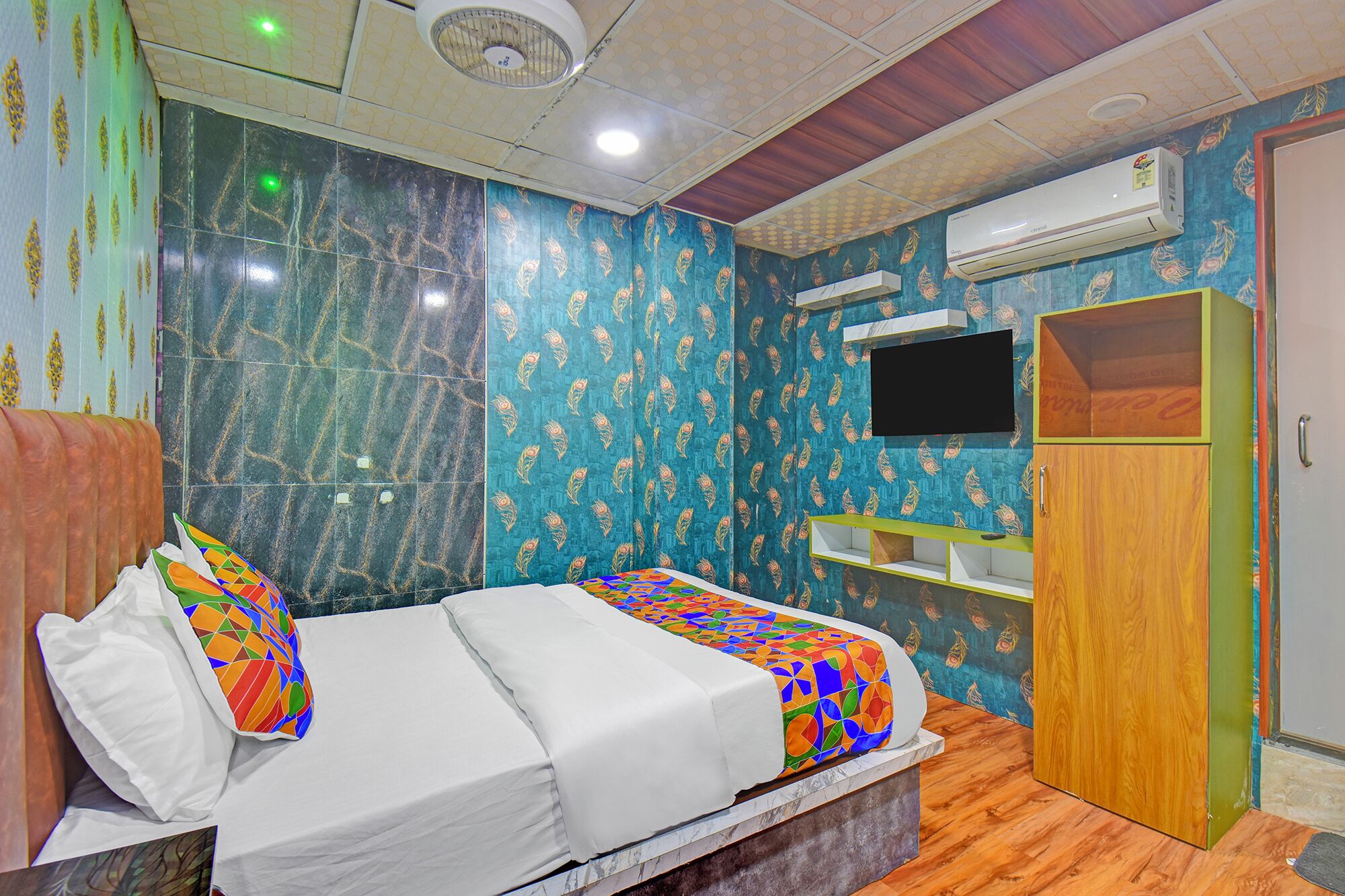 A bedroom with a bed, a TV, an air conditioner, and a wardrobe.
