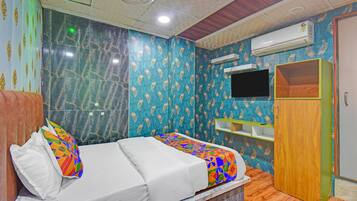 A bedroom with a bed, a TV, an air conditioner, and a wardrobe.