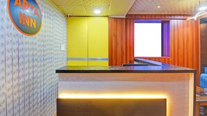 Un espace d’accueil avec un comptoir en bois, un mur jaune et une enseigne sur laquelle on peut lire « ARYA INN ».