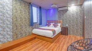 Une chambre à coucher avec un lit en bois, un papier peint à motifs floraux, une fenêtre avec des rideaux bleus et un appareil de climatisation.