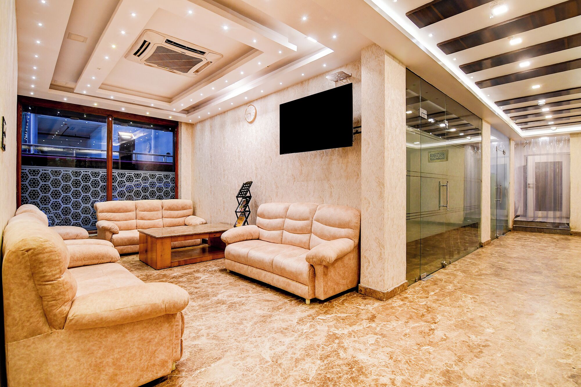 A modern lounge area with sofas, a coffee table, and a flat-screen TV mounted on the wall.