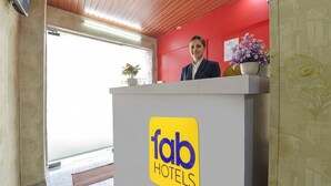 A reception desk with a 'fab hotels' logo, a receptionist, and a potted plant. - Fabhotel Silver Stay 02 (Jaipur)