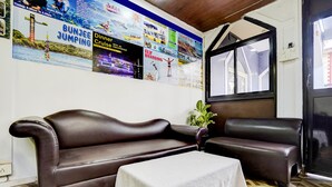 A room with a brown leather sofa, a small white table, and a poster advertising various activities. - Fabexpress Elvin Balaji Beach Palace (Calangute)