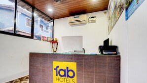 A hotel reception desk with a 'fab hotels' sign, an HP monitor, a printer, and air conditioning units above. - Fabexpress Elvin Balaji Beach Palace (Calangute)