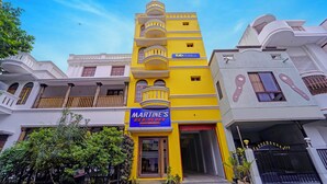 A multi-story building with a prominent yellow facade, a sign for 'Martine's Residency' indicating a residential property, and a 'fab hotels' sign suggesting nearby accommodation. - Fabhotel Martine Residency - French Colony, 5 Mins from Rock Beach (Puducherry)
