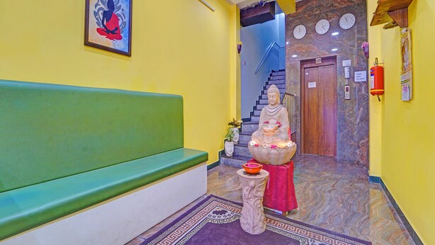 A reception area with a green bench, a Buddha statue, a clock, and a fire extinguisher. - Fabhotel Martine Residency - French Colony, 5 Mins from Rock Beach (Puducherry)