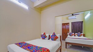 A hotel room with two beds, a wooden floor, a ceiling fan, and an air conditioning unit. - Fabhotel Martine Residency - French Colony, 5 Mins from Rock Beach (Puducherry)