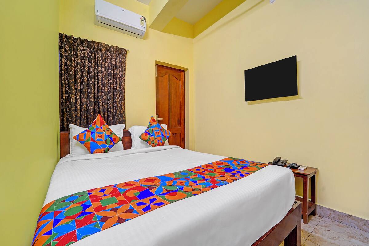 Habitación de hotel con cama, una puerta de madera, una pizarra y un teléfono sobre una mesa de madera.