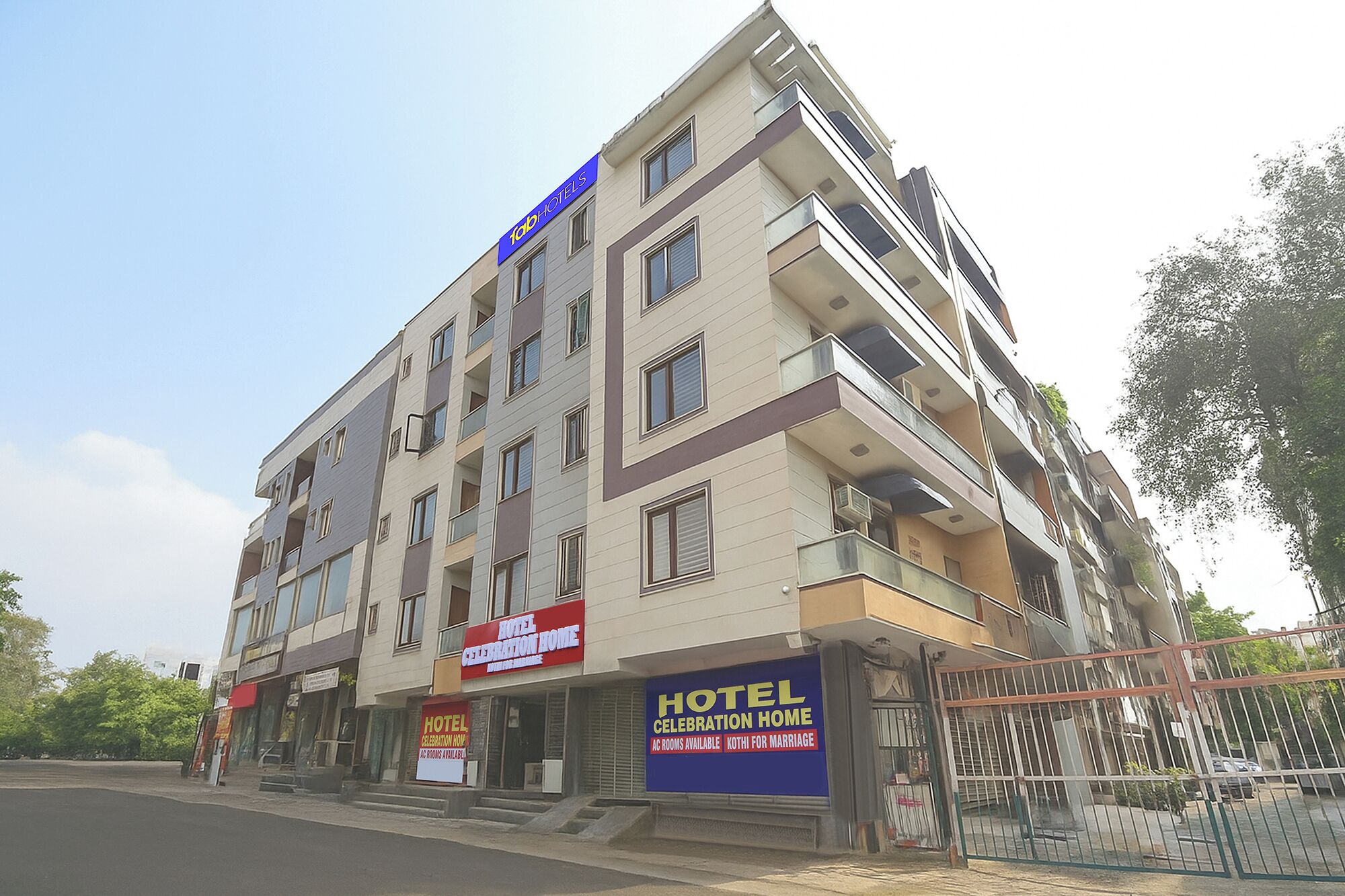A multi-story hotel with balconies, a sign for 'HOTEL CELEBRATION HOME', and a gated entrance.